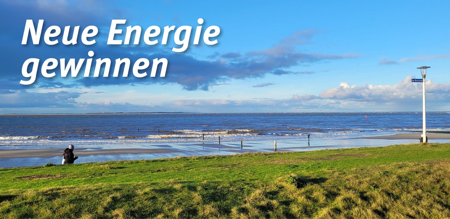 Grasbewachsene Düne, dahinter zwei Personen am Strand, dahinter Nordsee unter blauem Himmel mit Wolken. Die Überschrift auf dem Bild lautet: Neue Energie gewinnen.